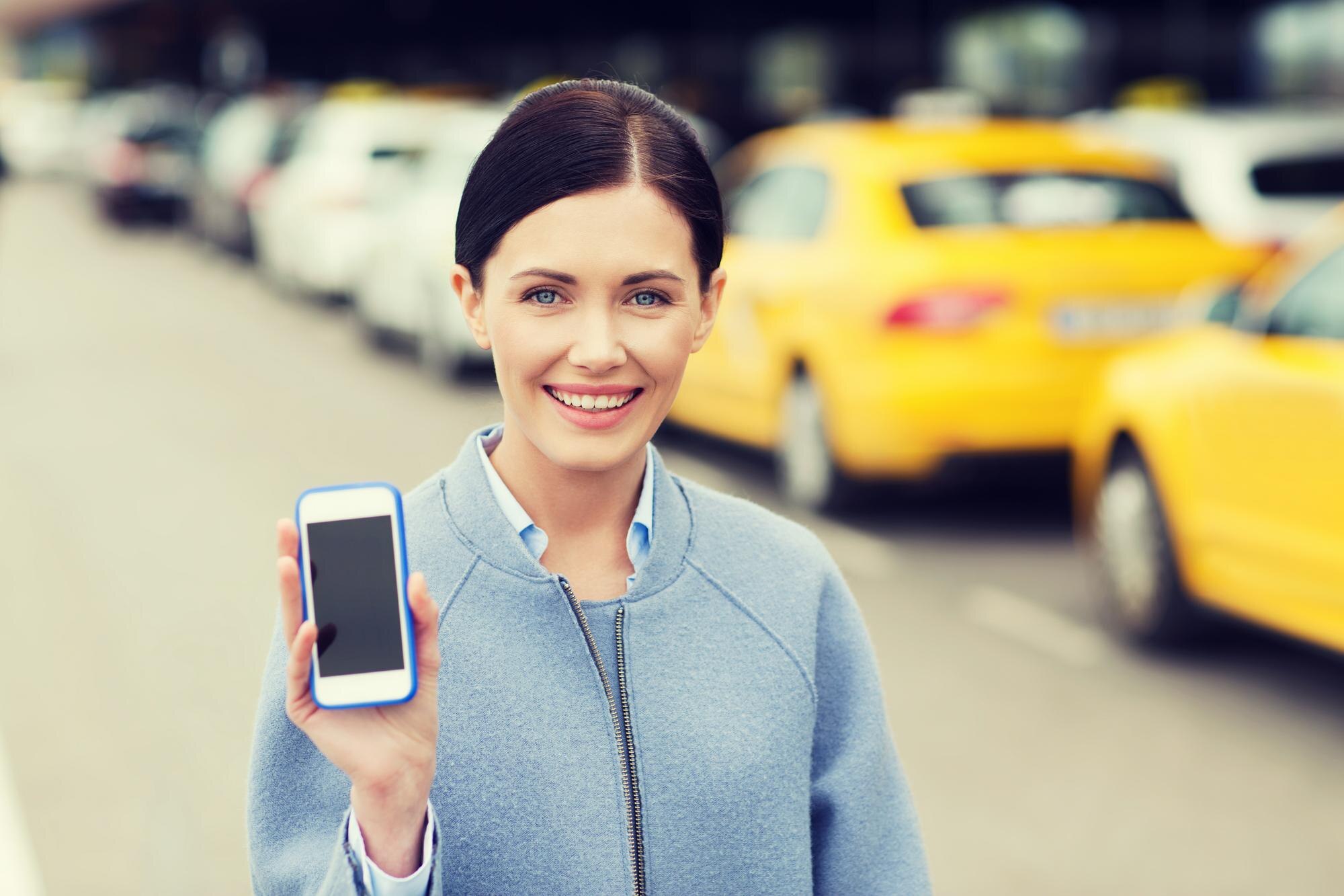 Nosheen Ramzan Yasmin - Servicios - travel business trip people tourism concept smiling young woman showing smartphone blank screen taxi